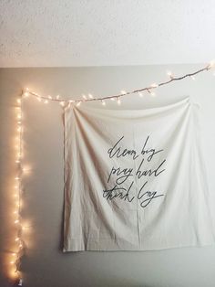 a white wall hanging on the side of a room with string lights and a sign that says dream by pizza hard thank you