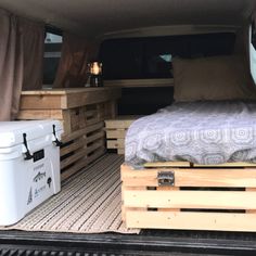 a bed made out of wooden pallets in the back of a truck with an ice chest