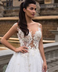 a woman in a white wedding dress standing on a bridge with her hands on her hips