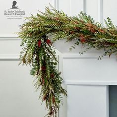 a christmas wreath is hanging on the front of a white fireplace with red berries and greenery