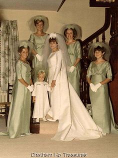 a group of women standing next to each other in front of a stair case wearing dresses and veils