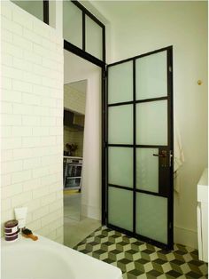 a bathroom with a black and white checkered floor, large glass door to the bathtub