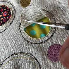 someone is using scissors to sew on some fabric with colorful circles and polka dots