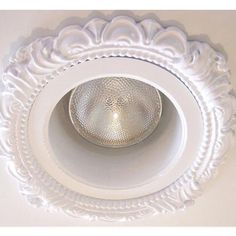 a light that is on top of a white ceiling fixture with filigrees