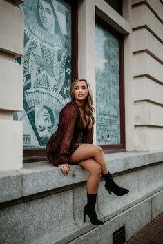 a beautiful woman sitting on the ledge of a building