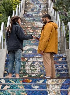 a man and woman standing on top of a set of stairs next to each other