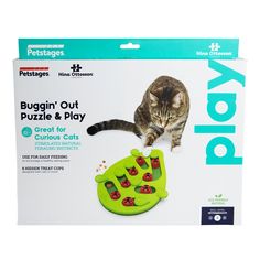 a cat playing with a puzzle and play toy in its packaging on a white background