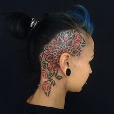 a woman with blue hair has a tattoo on her face and behind her ear is a flower