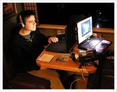 a man sitting at a table with a laptop computer and headphones on his ears