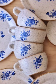 blue and white porcelain tea cups and saucers on a wooden table with matching plates