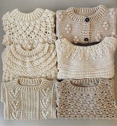 three crocheted sweaters and two pillow cases