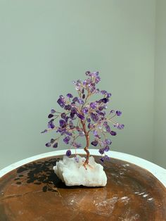 a small purple plant sitting on top of a wooden table