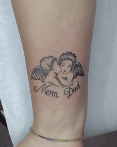 a woman's foot with an angel tattoo on her left leg and the words mom dad written in cursive font