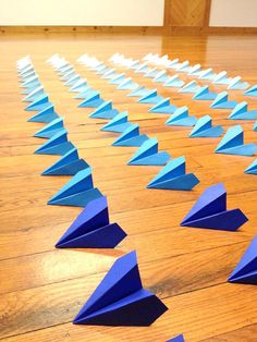 several blue paper airplanes are scattered on the floor in an empty room with wooden floors