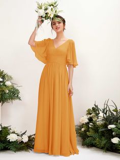 a woman in an orange dress is posing for the camera with flowers on her head