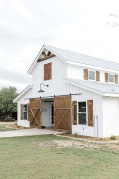 a large white barn with wooden doors and windows