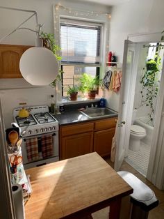 a kitchen with a stove top oven next to a sink and a wooden table in front of a window