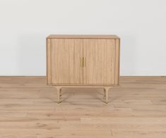 a wooden cabinet sitting on top of a hard wood floor next to a white wall