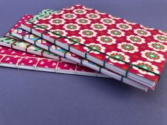 three notebooks are stacked on top of each other, one is red and the other is green