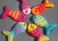 five different colored fish keychains on a gray surface with one in the middle