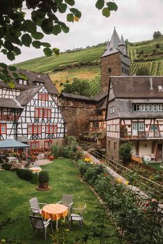 an image of a small town setting in the middle of mountains and greenery with tables and chairs