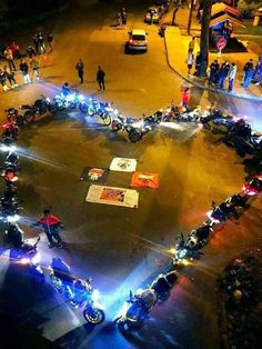 a group of motorcycles parked in a parking lot with lights on the side of it