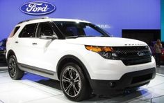 a white ford suv is on display at an auto show in front of a blue wall