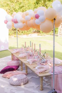 a table topped with lots of pink and white balloons