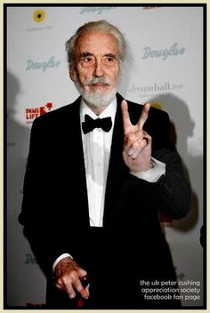 an older man in a tuxedo giving the peace sign