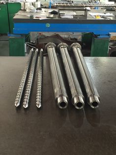 four stainless steel tubes are sitting on a table in front of a machine room filled with machinery