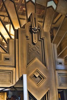 an art deco style clock on the side of a wall in a room with wooden paneling