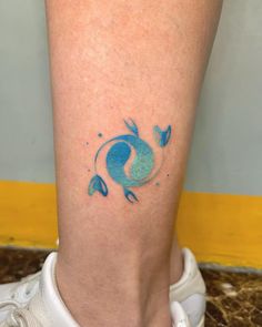 a small tattoo on the leg of a woman's foot with blue watercolors