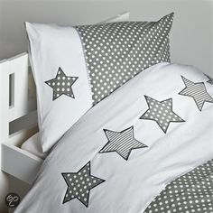 a bed with white and grey stars on the pillow cases, along with polka dot pillows