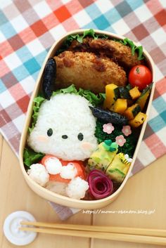 a bowl filled with rice and vegetables on top of a checkered table cloth next to utensils