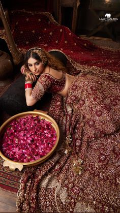 a woman sitting on a bed next to a bowl full of red cabbages in front of her