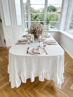 the table is set with pink flowers and place settings