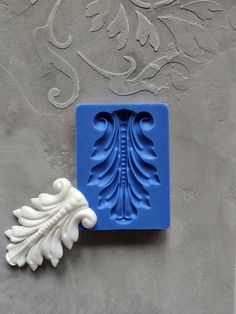 a blue and white mold sitting on top of a gray wall next to a leaf