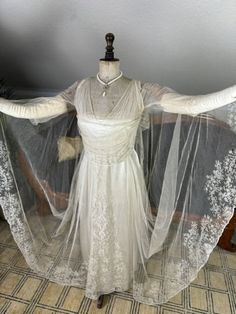 a dress on a mannequin with white lace and sheer fabric covering it's arms