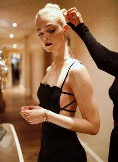 a woman in a black dress getting her hair done