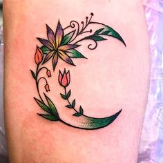 a tattoo design on the thigh of a woman's leg with flowers and leaves