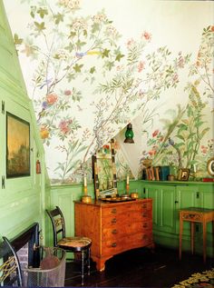 a room with green walls and floral wallpaper, including a dresser in the corner