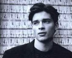 a black and white photo of a young man in front of a wall with letters on it