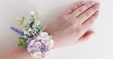 a woman's hand holding a bouquet of flowers and greenery on her wrist