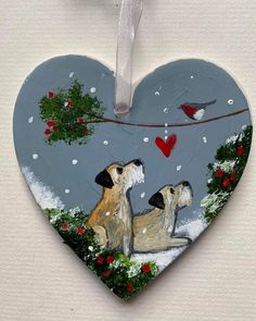 a heart shaped ornament with two dogs in the snow and a bird on it