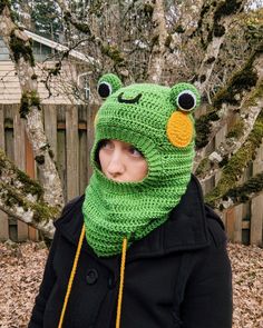 a child wearing a green frog hat and scarf