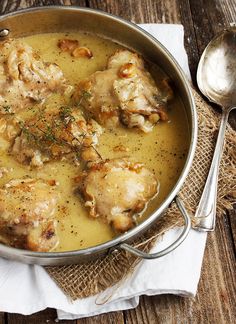 a pan filled with chicken and gravy on top of a wooden table