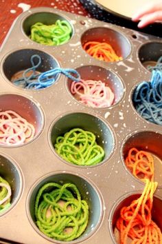 a muffin tin filled with lots of different colored noodles in it's pan