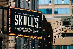 a sign that says skull's on it in front of some buildings with lights