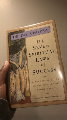 a person holding up a book about the seven spiritual laws of success by deepak chopra