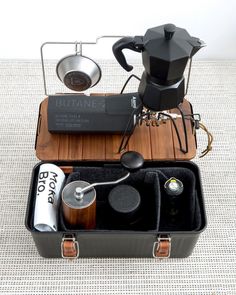 an open suitcase with various items in it sitting on a carpeted floor next to a coffee pot